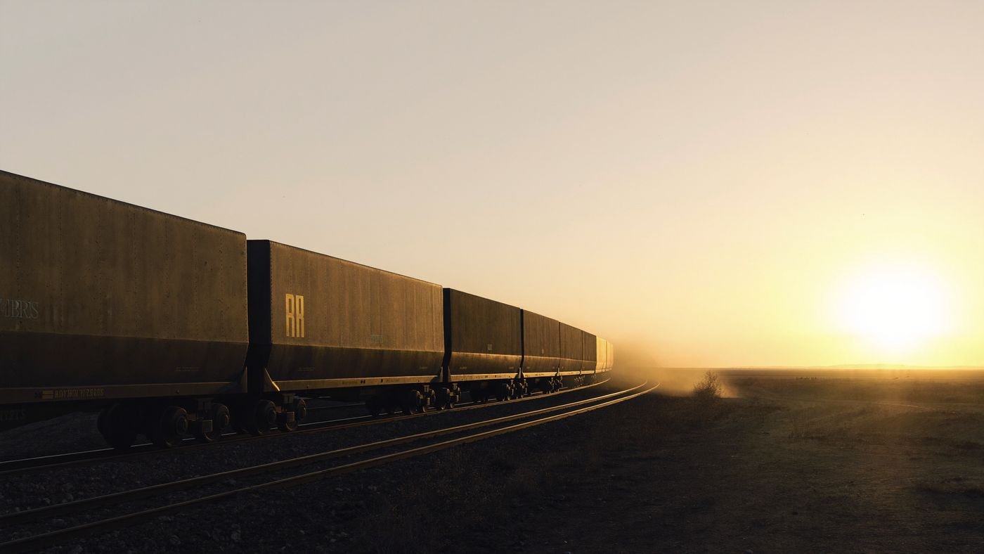 A freight train curving across open land at sunrise