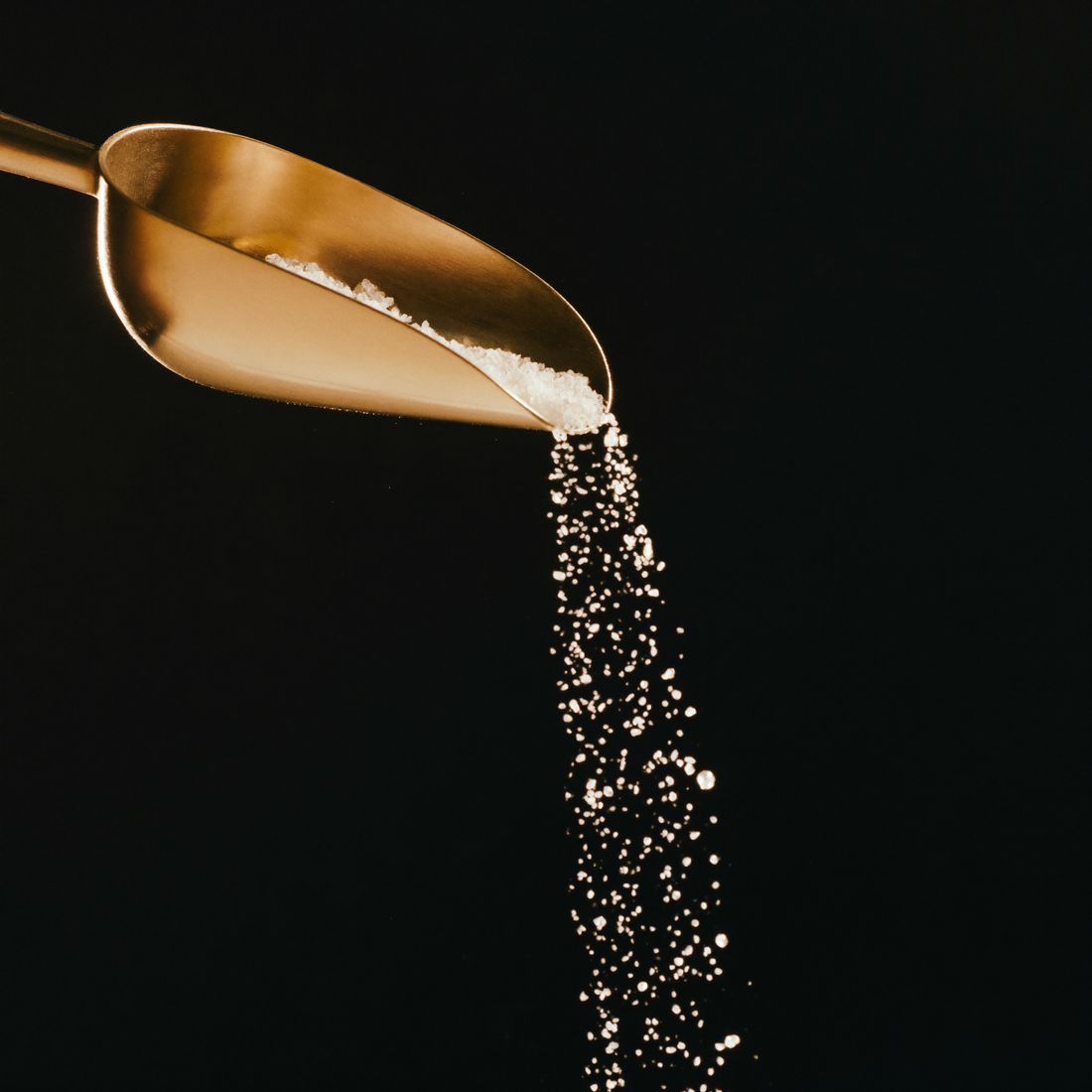A gold scoop pouring salt